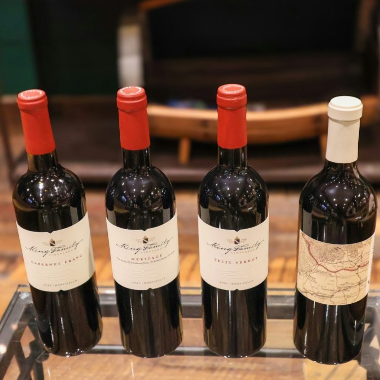 Outdoor patio furniture with pink cushions overlooking lush Kelowna's vineyard rows.